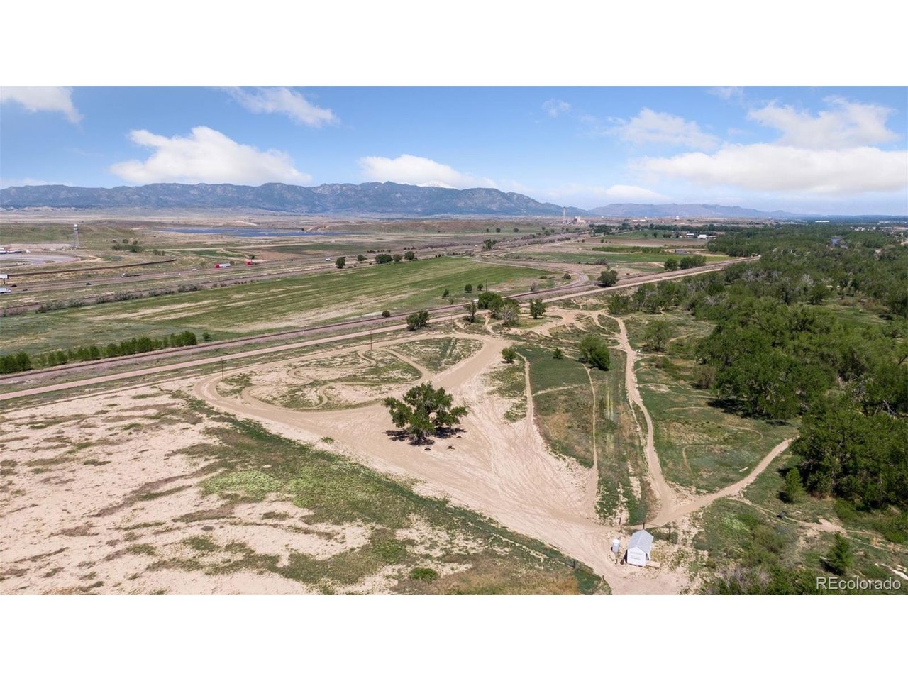 16880 Old Pueblo Road Fountain, CO 80817 - Photo 3 of 49 Elevated aerial showcasing the entrance/base area of the established Fountain Motorsports Park and riding trail system, predominantly level terrain, and expansive views toward the Front Range, illustrating the recreational scale of the land.
