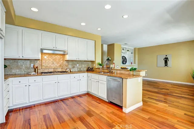 a kitchen with stainless steel appliances granite countertop a stove a sink and a white cabinets