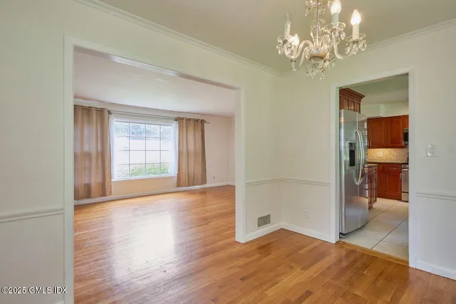 an empty room with wooden floor chandelier and windows