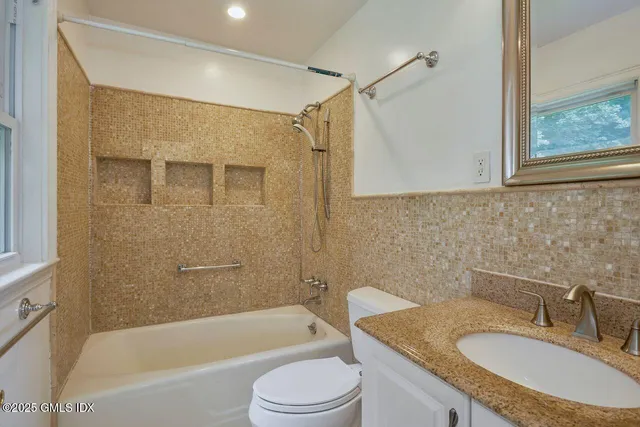 a bathroom with a granite countertop sink toilet tub and shower
