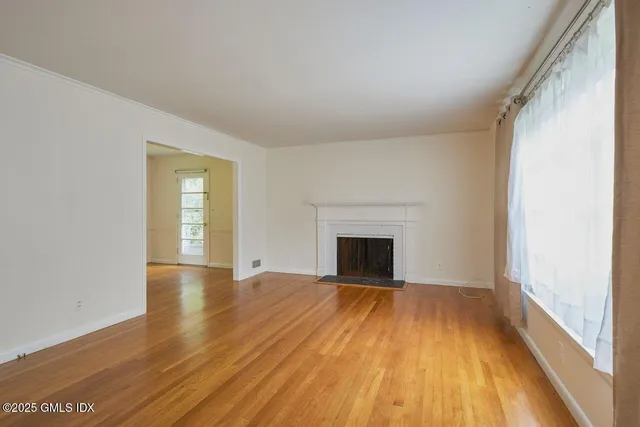 a view of empty room with wooden floor and fireplace
