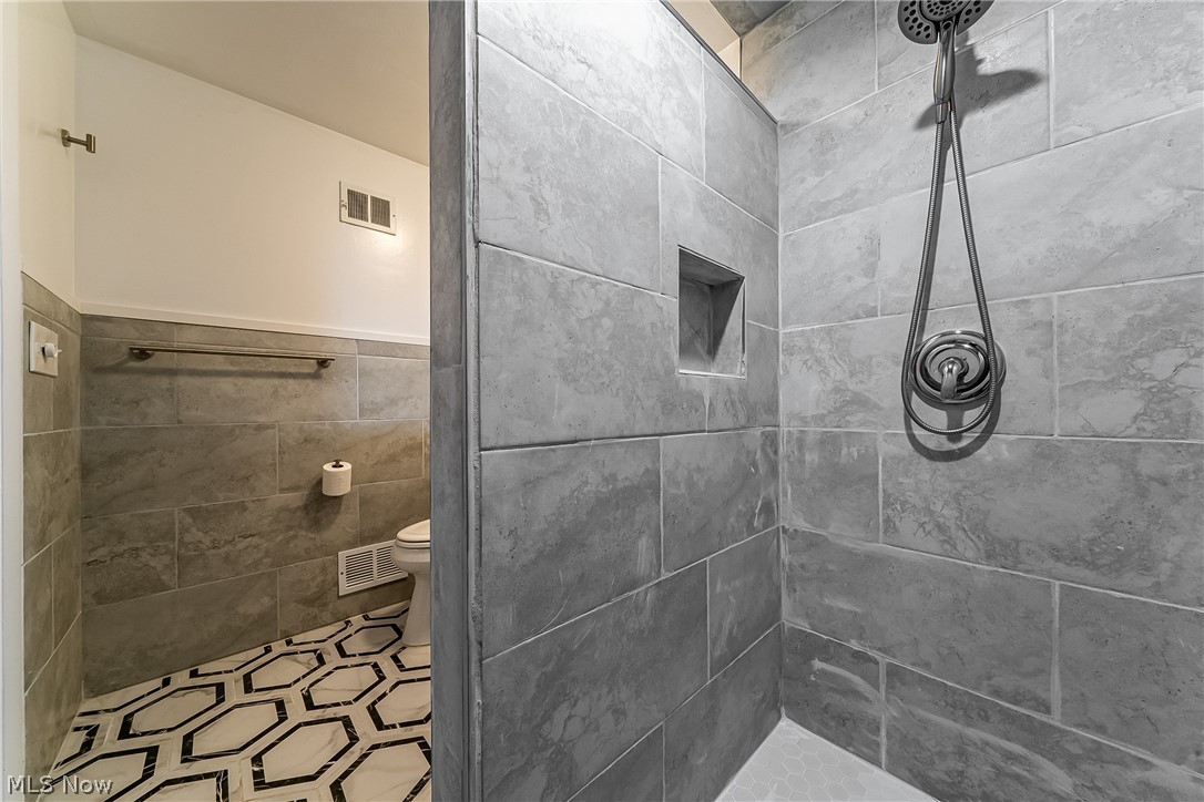 13800 Fairhill Road, Unit 306 Cleveland, OH 44120 - Photo 14 of 48 Updated en-suite bath off the primary suite featuring a tiled walk-in shower, modern vanity, stylish wainscoting, and contemporary tile finishes throughout.
