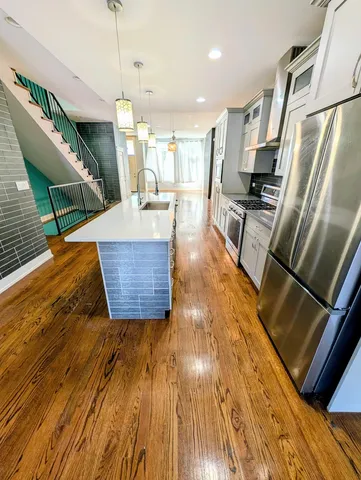 a living room with stainless steel appliances furniture and a kitchen view
