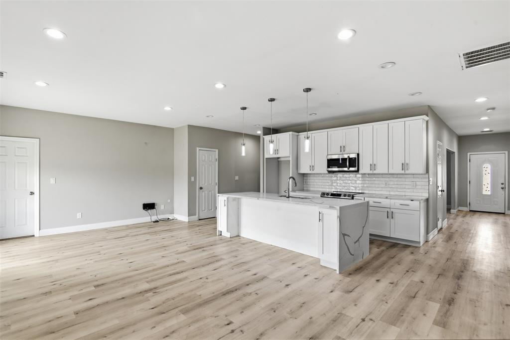 2204 Albert Broadfoot Street Bonham, TX 75418 - Photo 11 of 39 a large kitchen with cabinets wooden floor and stainless steel appliances