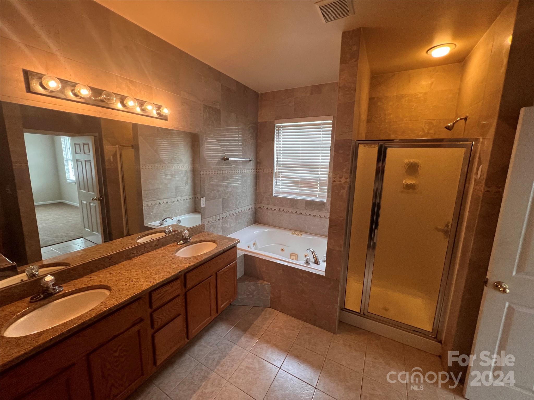1022 Breakmaker Lane Indian Trail, NC 28079 - Photo 8 of 20 a spacious bathroom with a double vanity sink a mirror and a bathtub