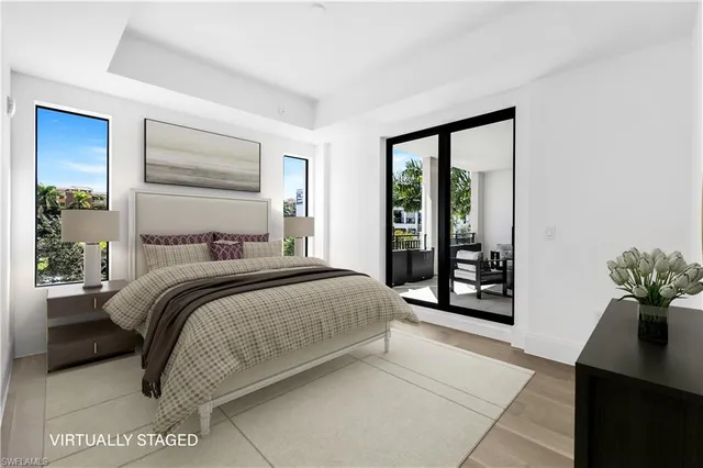 a bedroom with a balcony a bed and a potted plant next to a window