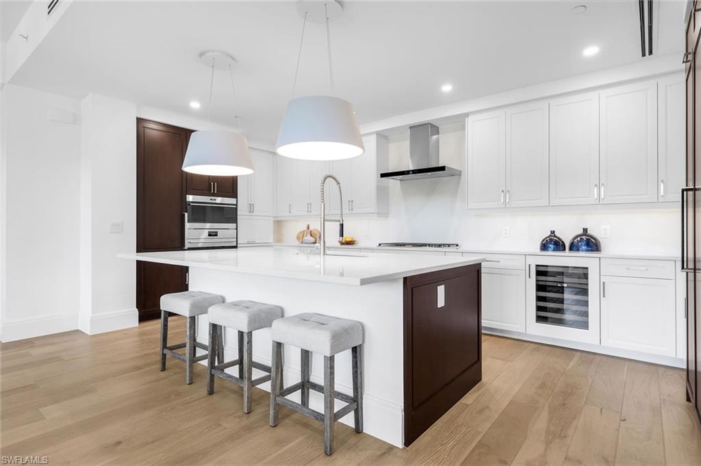 1130 3rd Avenue South, Unit 211 Naples, FL 34102 - Photo 7 of 33 a kitchen with stainless steel appliances granite countertop a stove top oven a sink dishwasher and a refrigerator with wooden floor