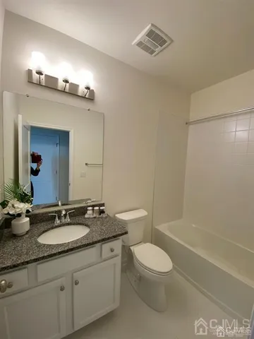 a bathroom with a granite countertop sink a toilet a mirror and shower