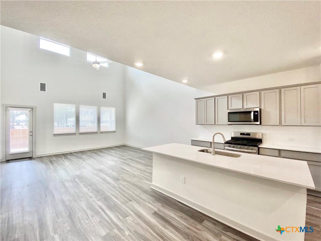 100 Geminiflora Bend Leander, TX 78641 - Photo 11 of 38 a kitchen with stainless steel appliances a stove top oven a sink a refrigerator white cabinets and wooden floor