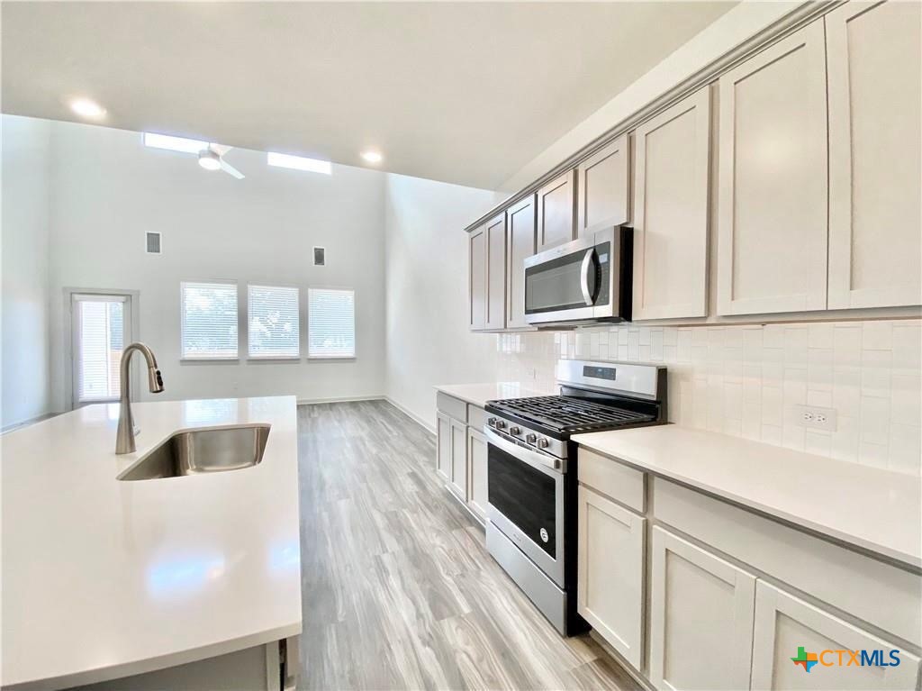 100 Geminiflora Bend Leander, TX 78641 - Photo 10 of 38 a kitchen with granite countertop a sink a stove and cabinets