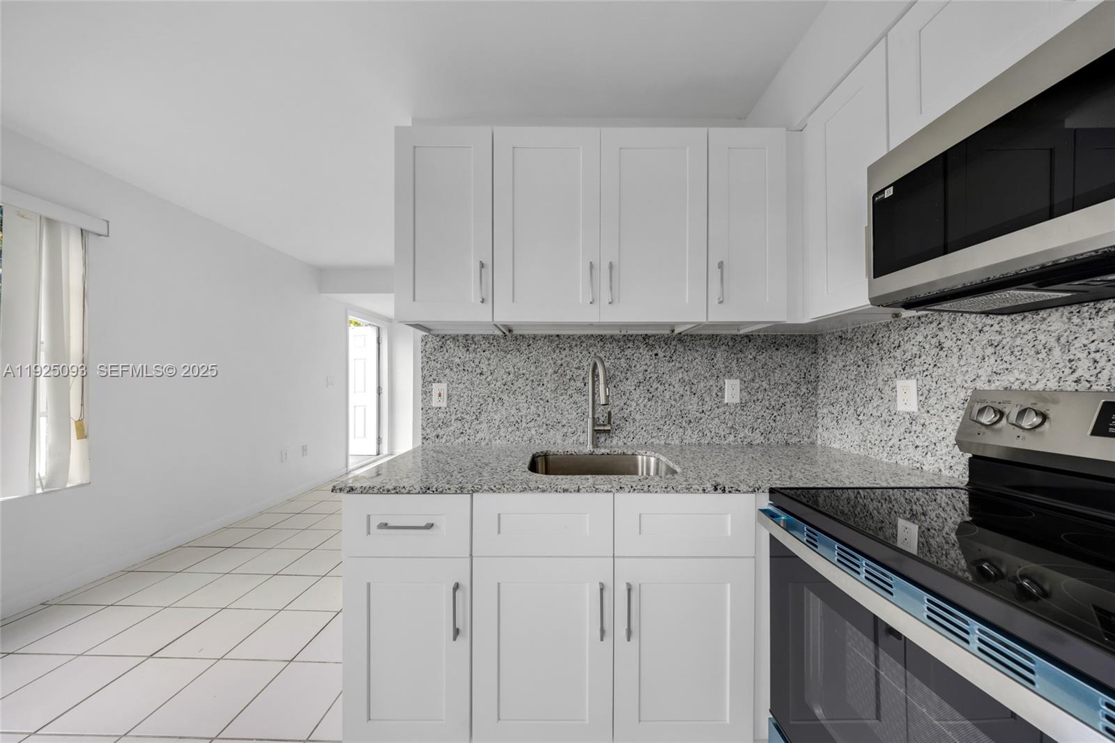 3453 Southwest 23rd Terrace, Unit 1 Miami, FL 33145 - Photo 7 of 22 a kitchen with stainless steel appliances granite countertop a sink stove and microwave