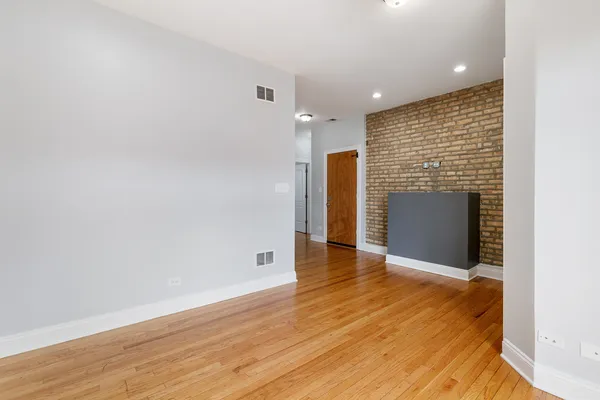 a view of an empty room with wooden floor and a fireplace