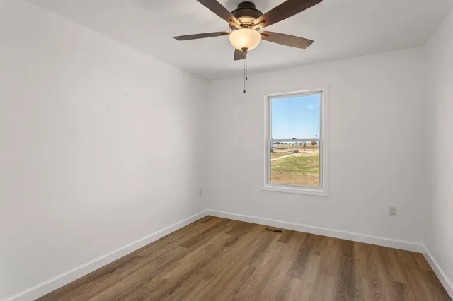an empty room with a window and wooden floor
