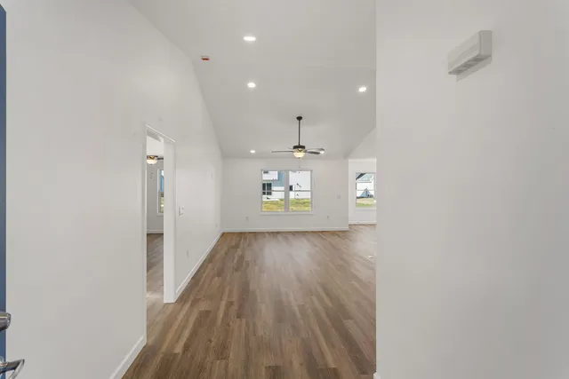 a view of a hallway with wooden floor and a refrigerator