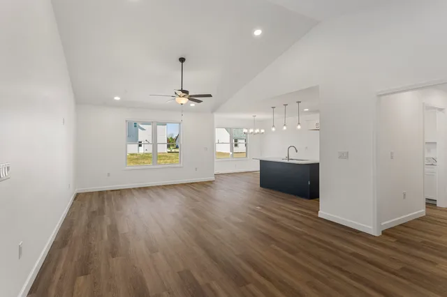 an empty room with wooden floor chandelier and windows