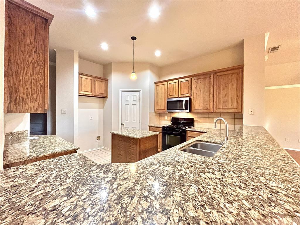 4808 Heber Springs Trail Fort Worth, TX 76244 - Photo 7 of 16 a kitchen with granite countertop a stove top oven a sink dishwasher and a refrigerator with wooden floor