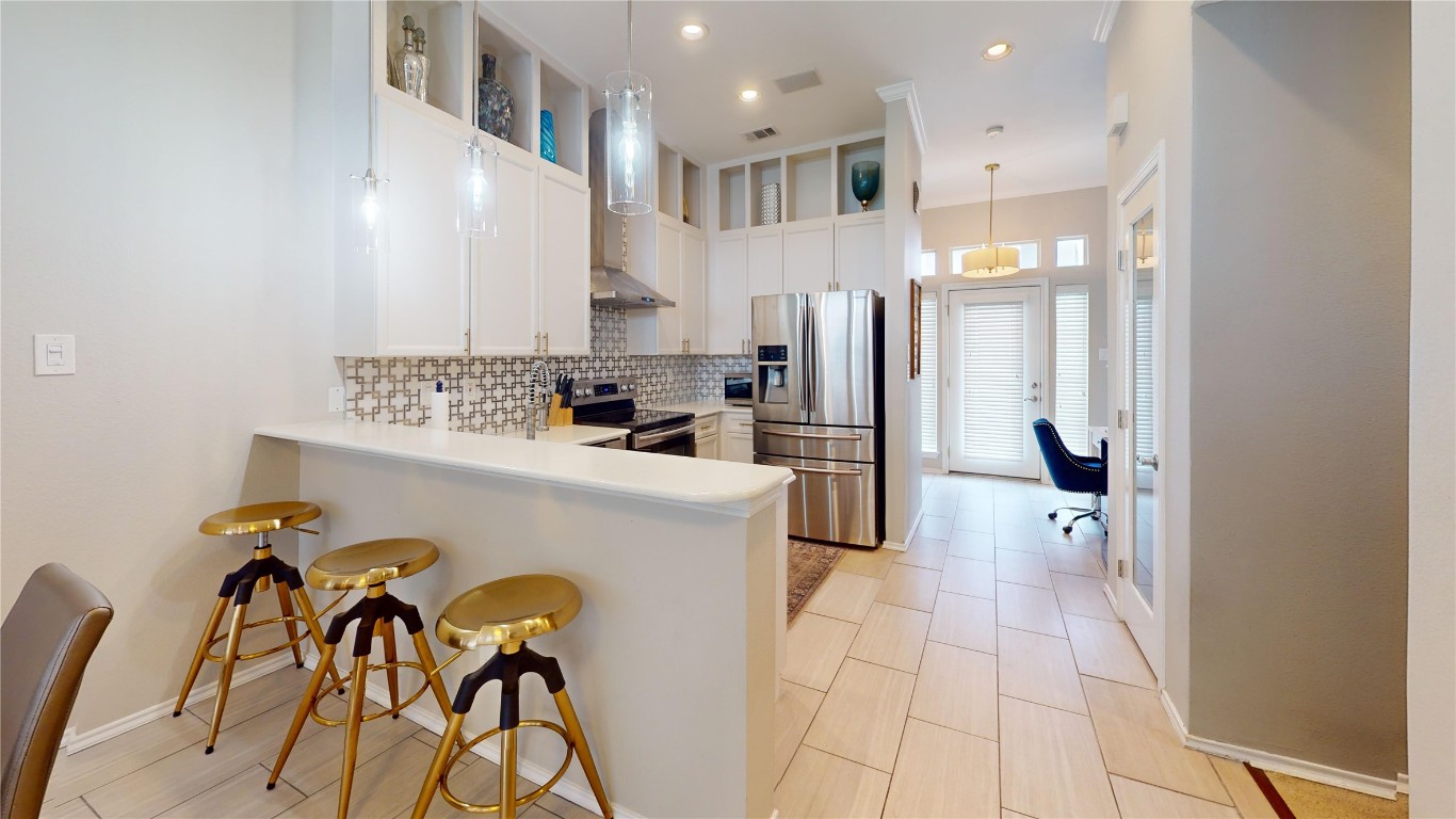 2918 Ranch Road 620, Unit 297 Austin, TX 78734 - Photo 5 of 37 Kitchen with stainless steel appliances, a peninsula, tasteful backsplash, a kitchen bar, and light countertops