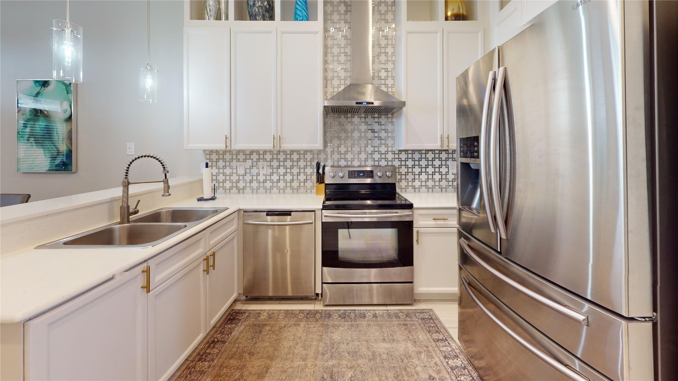 2918 Ranch Road 620, Unit 297 Austin, TX 78734 - Photo 7 of 37 Kitchen featuring appliances with stainless steel finishes, wall chimney range hood, light countertops, and white cabinets