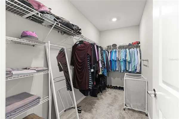 a view of walk in closet with clothes and shoes