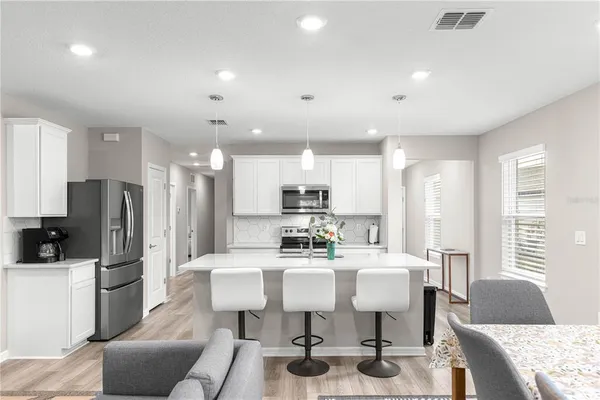 a kitchen with stainless steel appliances kitchen island granite countertop a refrigerator a stove a sink dishwasher with a dining table and chairs