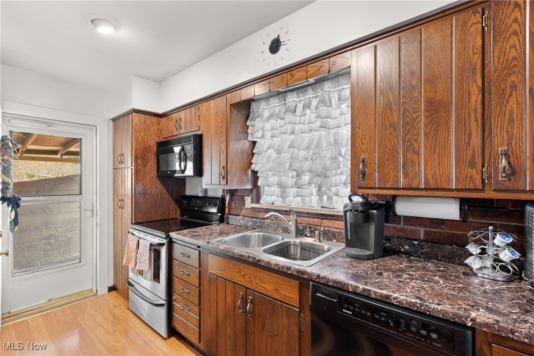 8 Spring Street Bridgeport, OH 43912 - Photo 6 of 34 Kitchen featuring dark countertops, black appliances, light wood-style floors, and backsplash
