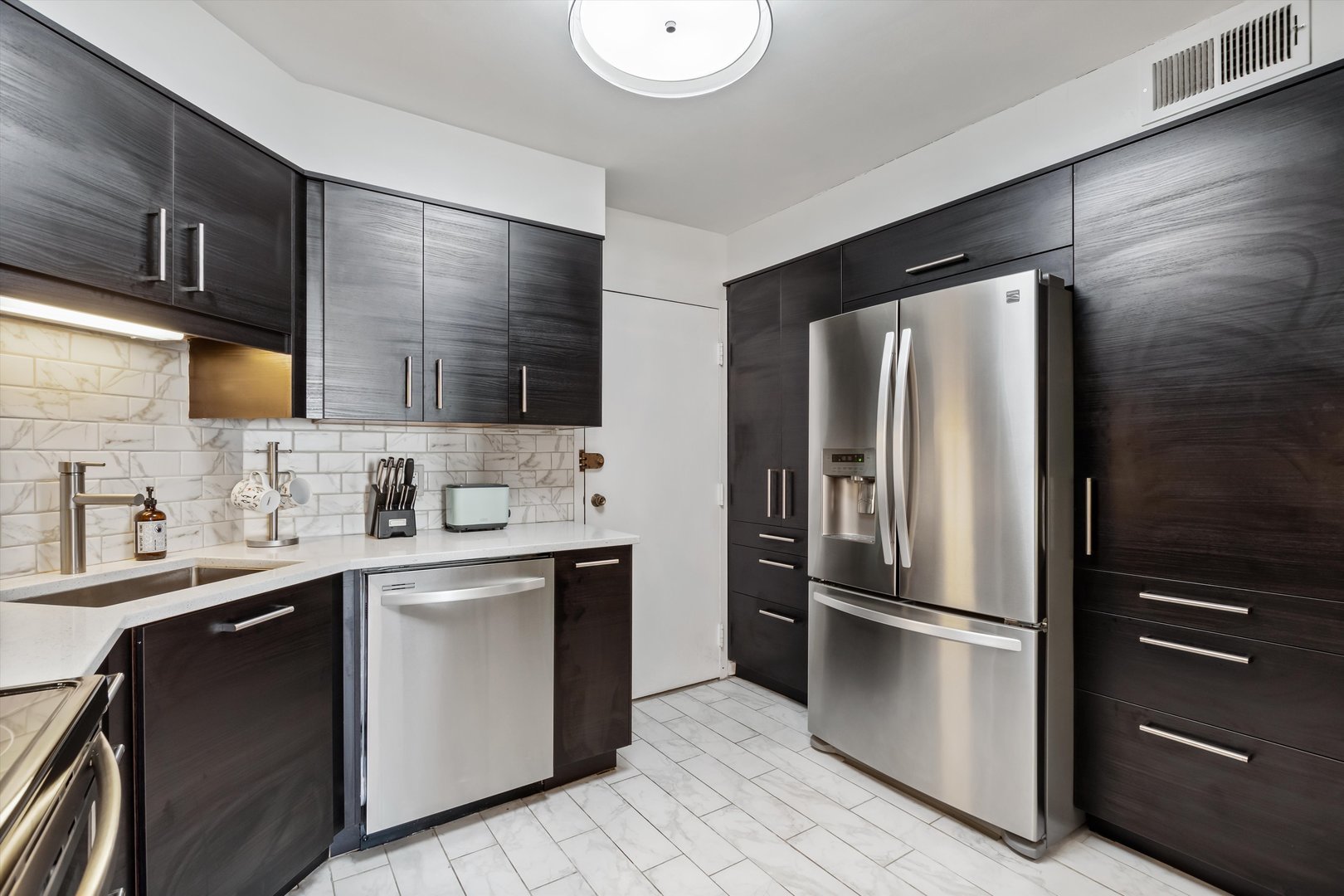 6033 North Sheridan Road, Unit 21D Chicago, IL 60660 - Photo 5 of 22 a kitchen with a sink stainless steel appliances and cabinets