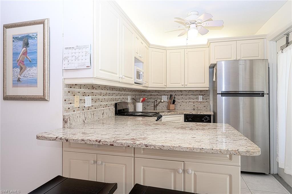 637 12th Avenue South, Unit 637 Naples, FL 34102 - Photo 6 of 35 a kitchen with kitchen island granite countertop a refrigerator a sink and white cabinets
