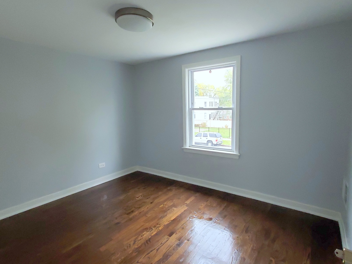 653 East 105th Street Chicago, IL 60628 - Photo 13 of 27 an empty room with wooden floor and windows