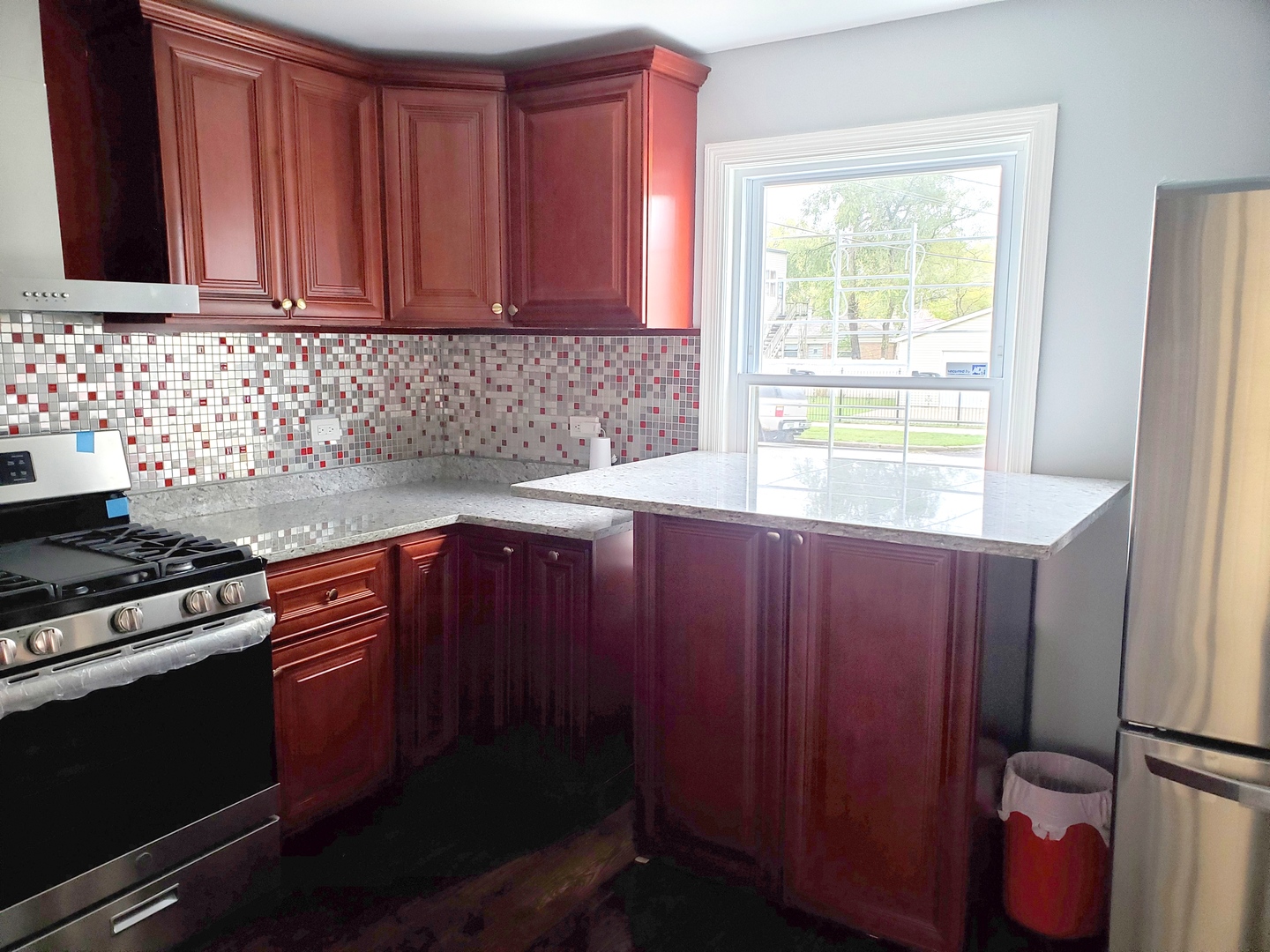 653 East 105th Street Chicago, IL 60628 - Photo 10 of 27 a kitchen with granite countertop wooden cabinets and a stove top oven