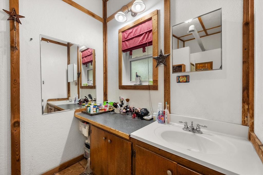 126 Smallwood Court Springtown, TX 76082 - Photo 17 of 24 Primary Bathroom featuring wood-finish framing, a window with a red blind, and an integrated vanity sink with a chrome faucet