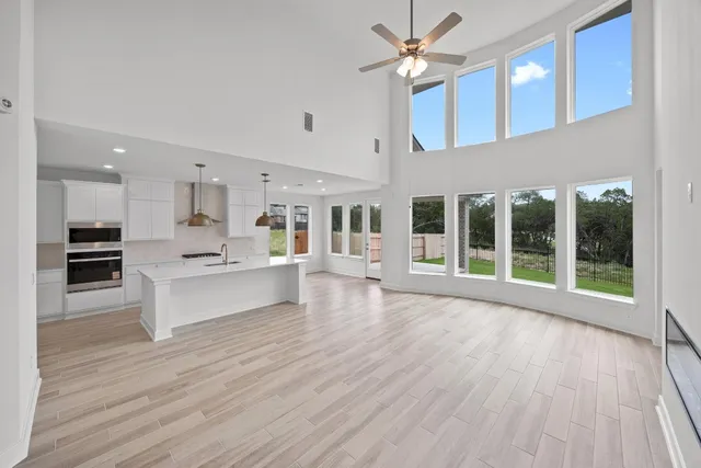 a living room with stainless steel appliances kitchen island hardwood floor and a large window