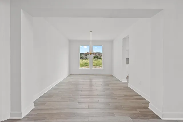 a view of an empty room with window and wooden floor