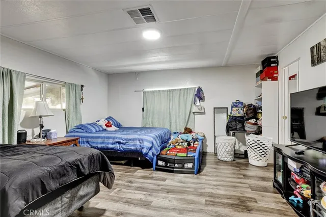 a bedroom with bed a flat tv screen and a dresser