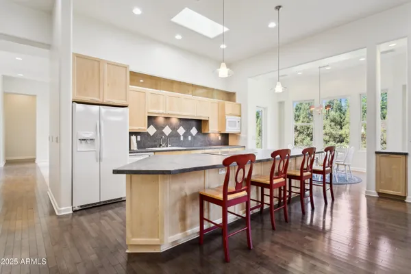 a kitchen with stainless steel appliances granite countertop a kitchen island hardwood floor and a sink