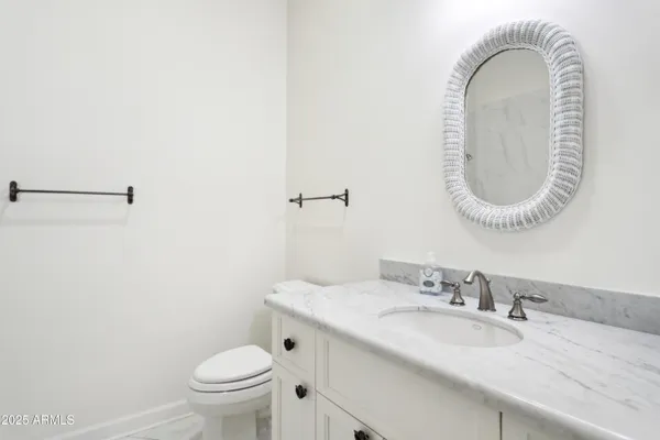 a bathroom with a granite countertop toilet a sink and a mirror