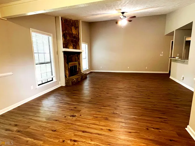 an empty room with wooden floor fireplace and windows