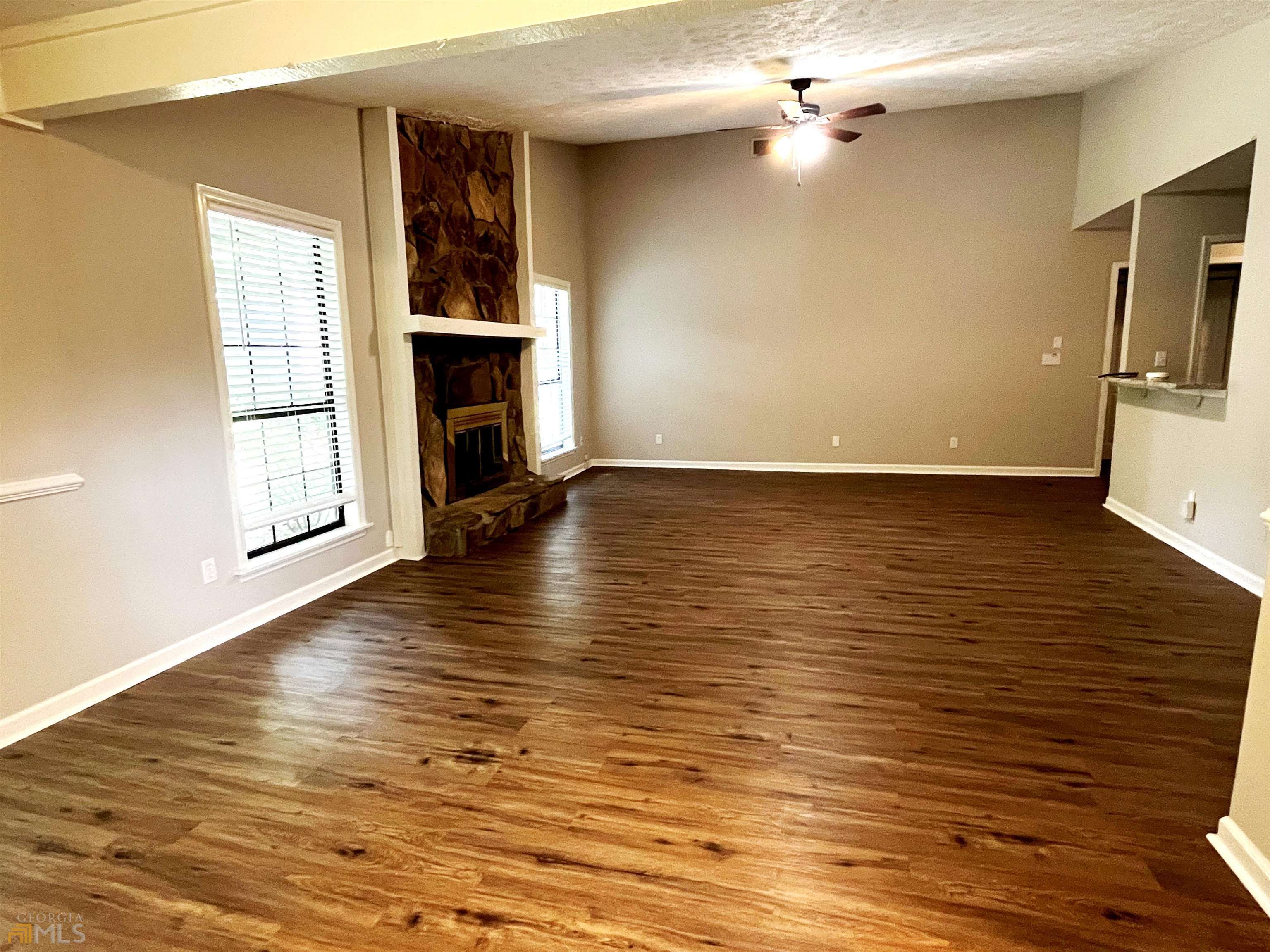 320 Broken Lance Place Alpharetta, GA 30022 - Photo 3 of 18 an empty room with wooden floor fireplace and windows