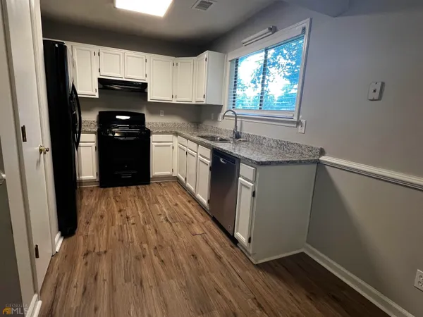 a kitchen with granite countertop wooden floors a sink and a stove