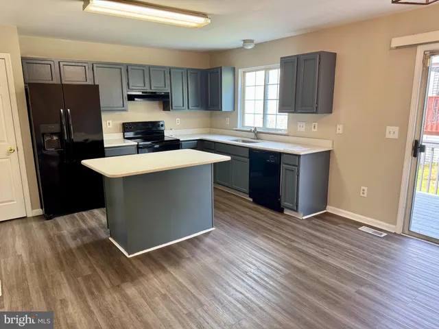 a kitchen with kitchen island a sink dishwasher a refrigerator and a stove with wooden floor