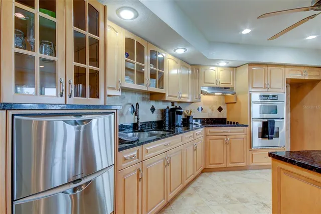 a large kitchen with stainless steel appliances granite countertop a sink counter space cabinets and a counter top space