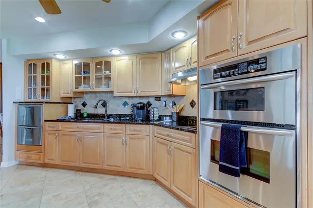a kitchen with stainless steel appliances kitchen island granite countertop a table chairs sink and cabinets