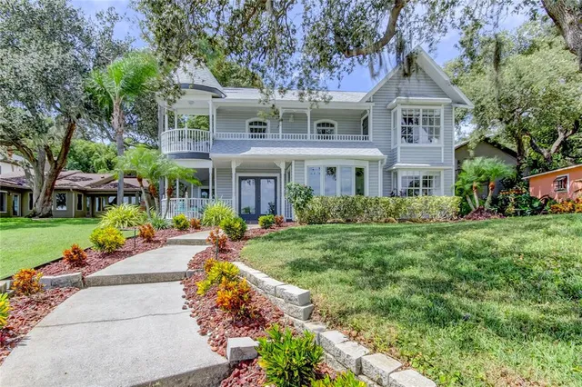 a front view of a house with a garden and trees