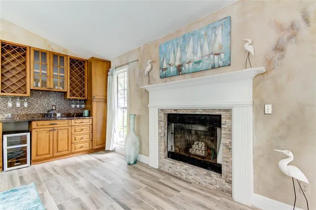 a living room with stainless steel appliances granite countertop a fireplace and a refrigerator
