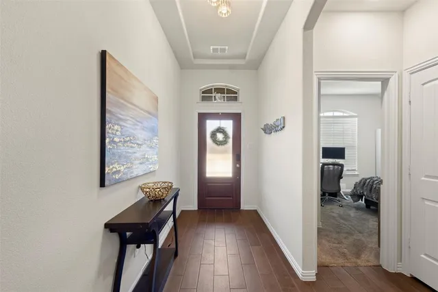 a view of a hallway with entryway wooden floor and windows