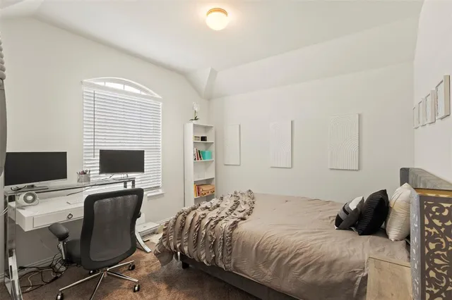 a bedroom with a bed and a computer on a desk next to a window