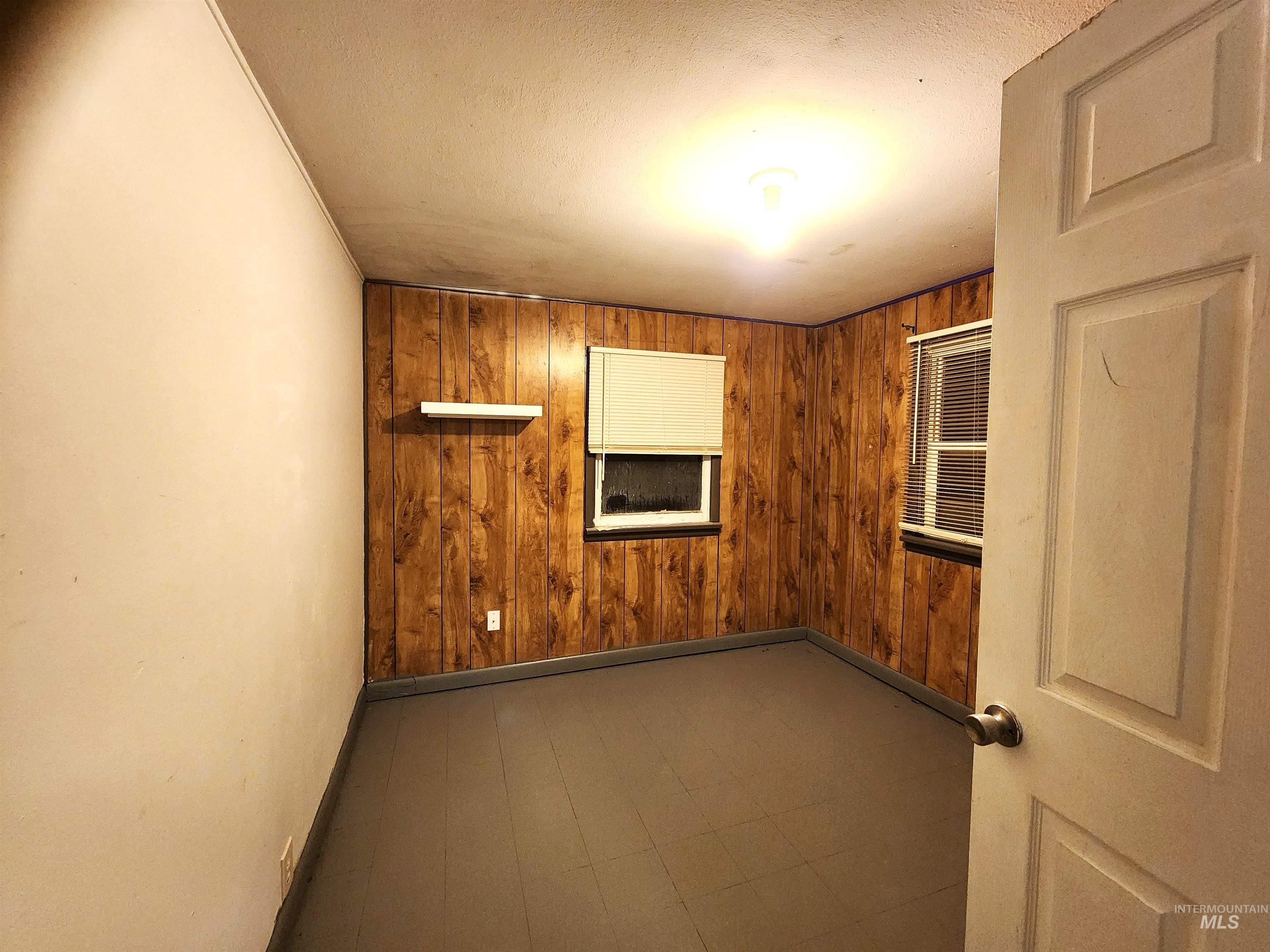 188 Morton Street West Vale, OR 97918 - Photo 4 of 9 Empty room featuring wood walls and a textured ceiling