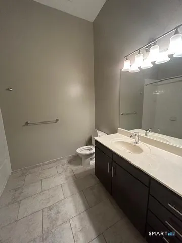 a bathroom with a granite countertop sink a toilet and a mirror