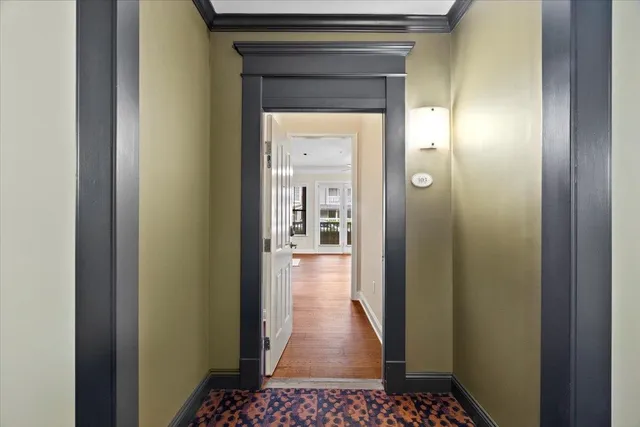 a view of a hallway view with wooden floor and a bathroom