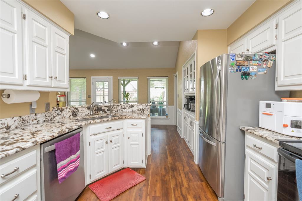116 Meadowglen Circle Coppell, TX 75019 - Photo 8 of 32 a kitchen with granite countertop a refrigerator a sink dishwasher a stove and white cabinets with wooden floor