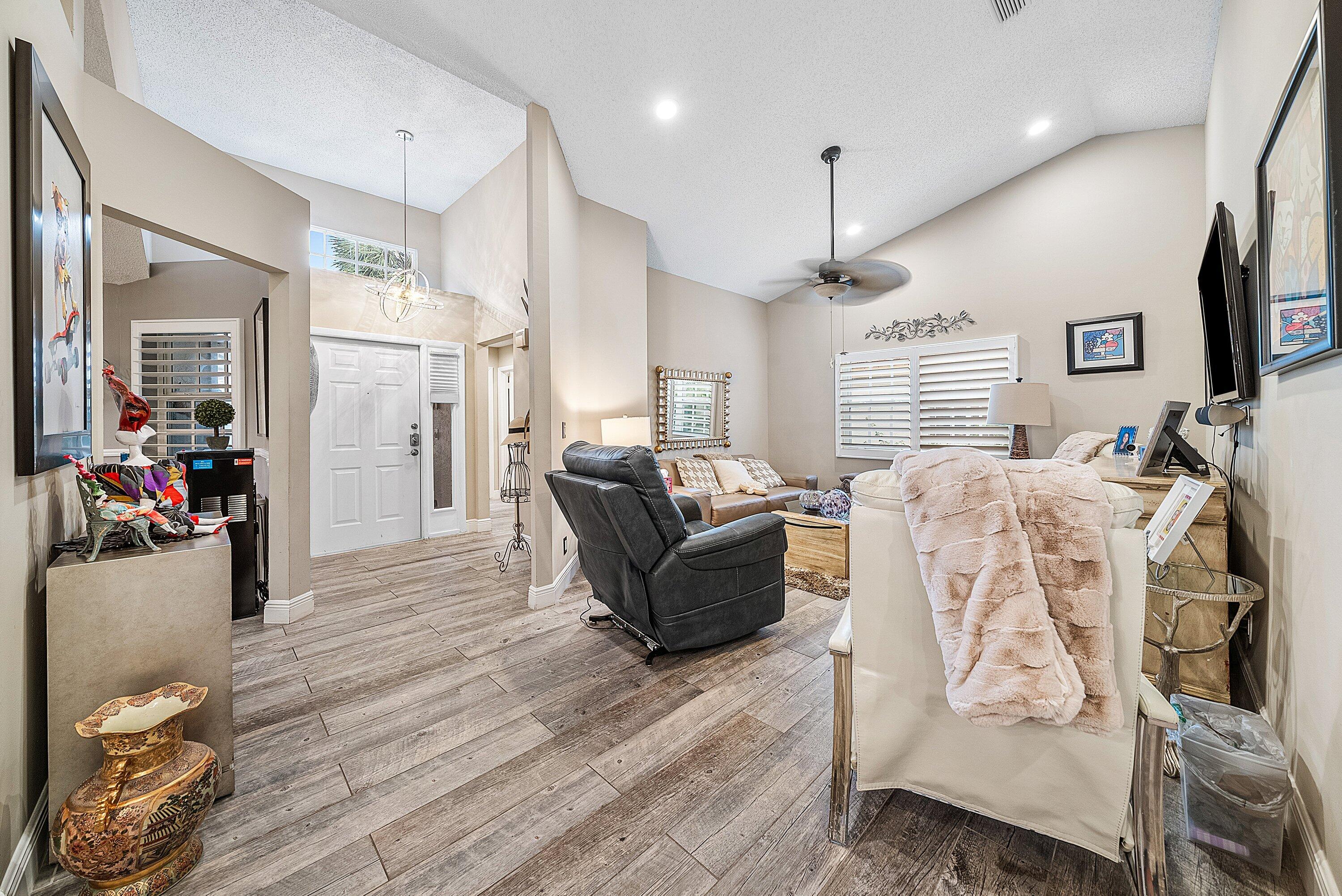 14338 Ruby Pointe Drive Delray Beach, FL 33446 - Photo 16 of 36 a living room with furniture a flat screen tv and kitchen view
